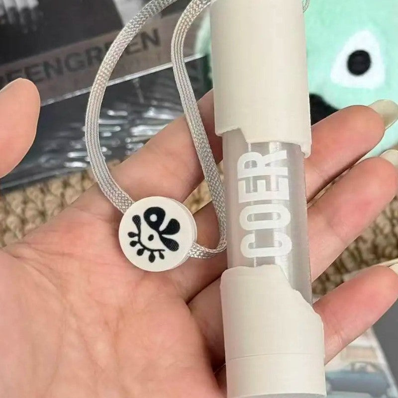 CORTIS mini LED lightstick keychain with white casing and a charm on a grey lanyard