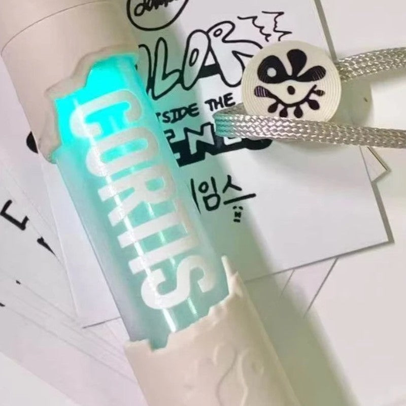 CORTIS mini LED lightstick keychain glowing cyan with an eye-pattern charm