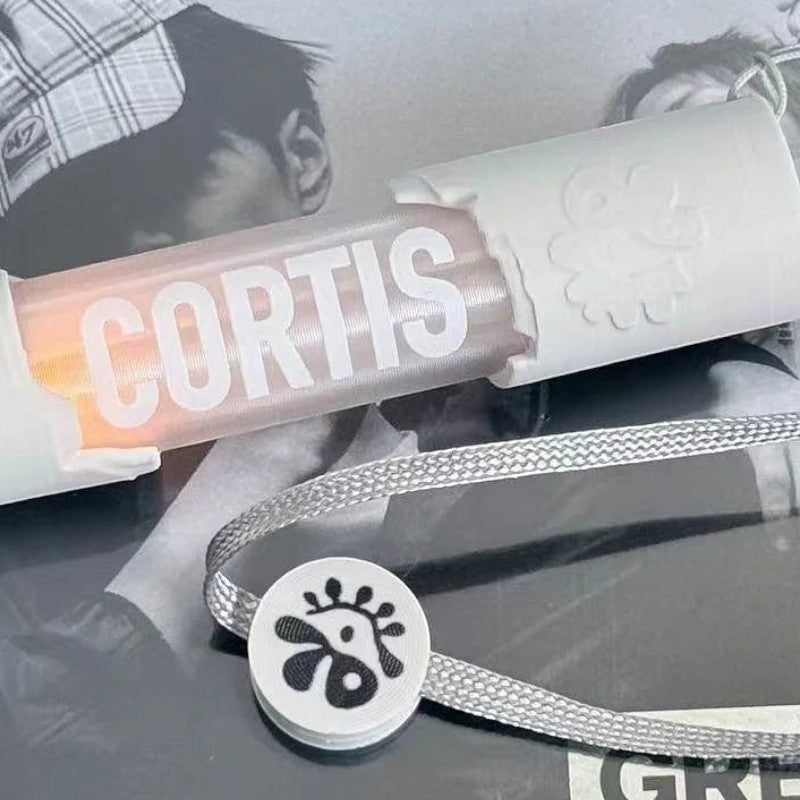 CORTIS mini LED lightstick keychain with white casing and a branded grey lanyard