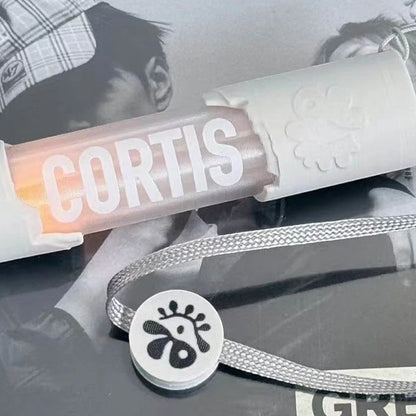 CORTIS mini LED lightstick keychain with white casing and a branded grey lanyard