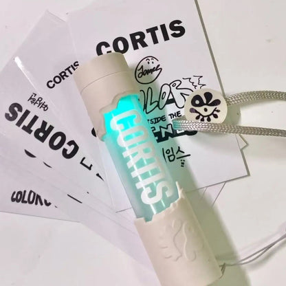 CORTIS mini LED lightstick keychain glowing cyan with a white textured casing